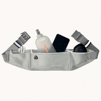 A light gray Strive brand waist bag filled with various items like a water bottle, phone, and earbud case, shown against a plain off-white background.