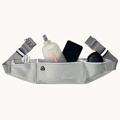 A light gray Strive brand waist bag filled with various items like a water bottle, phone, and earbud case, shown against a plain off-white background.